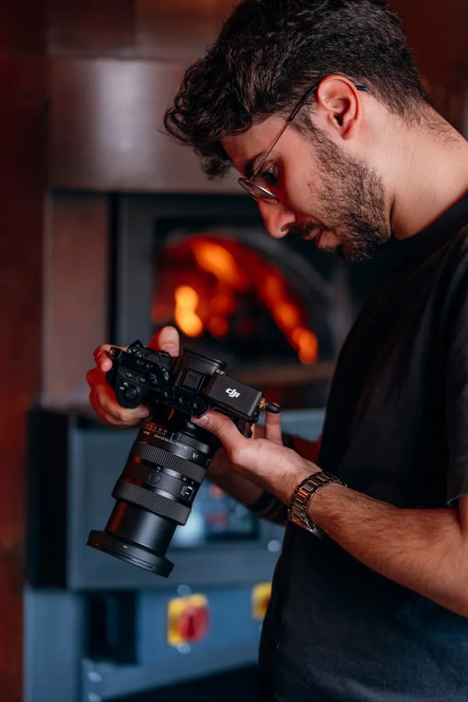 O fotógrafo junto ao forno a lenha, a ver a câmara