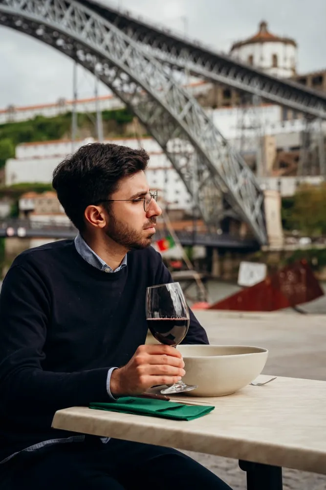 Um cliente com um copo de vinho, com a ponte D. Luís atrás