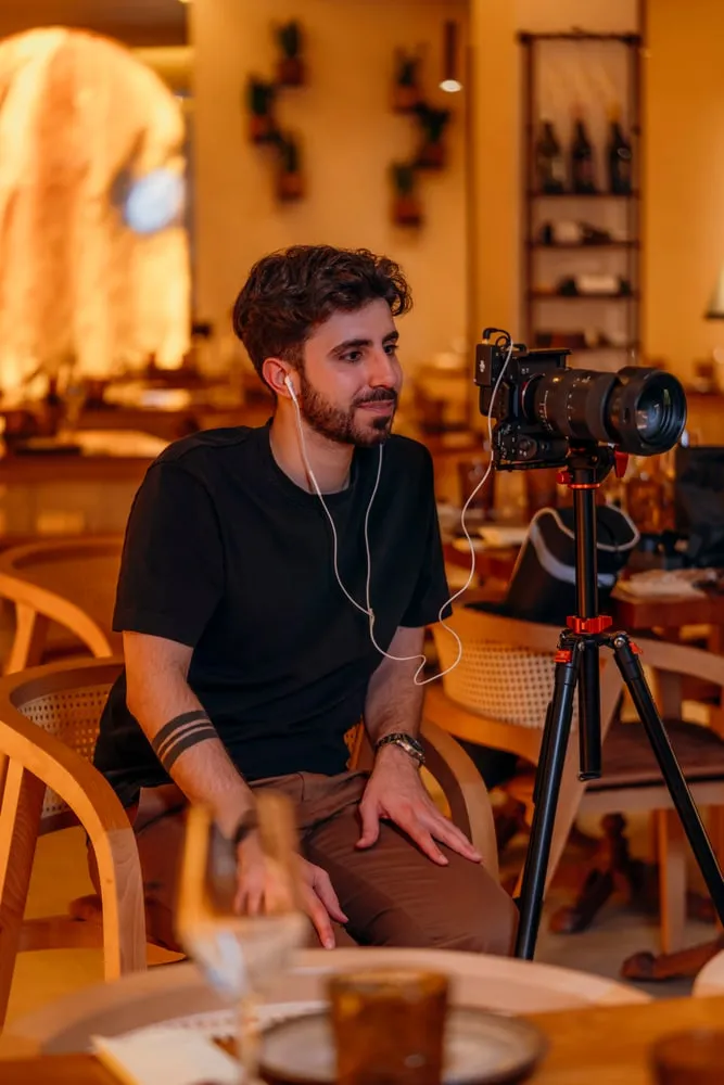 O videógrafo com a câmara no tripé, na sala de um restaurante