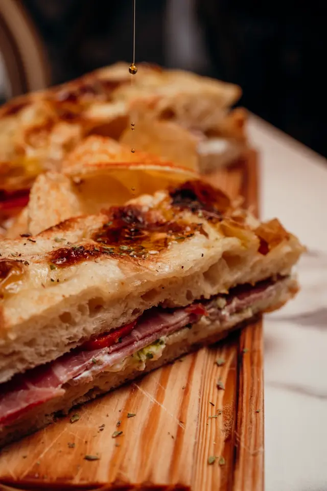 Focaccia com presunto e queijo, com um fio de mel a cair